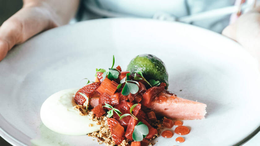 A person holding a plate of food on top of a table.