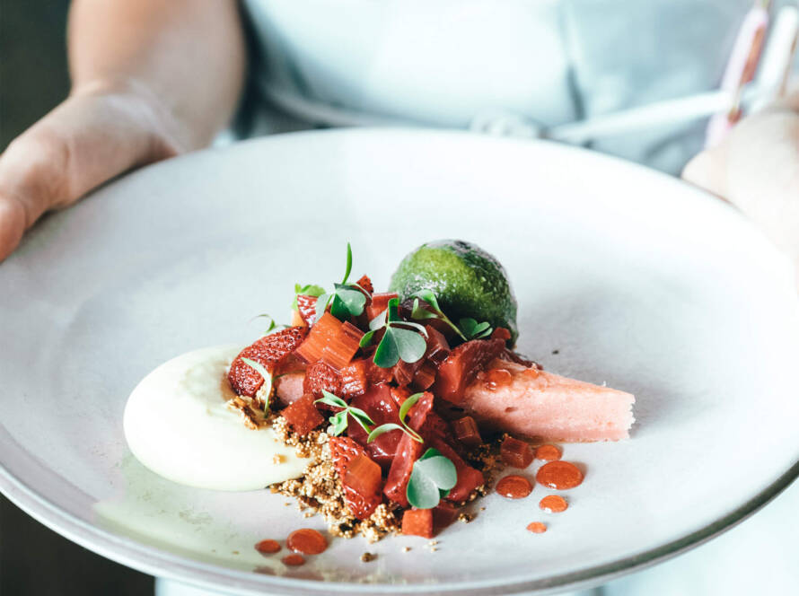 A person holding a plate of food on top of a table.
