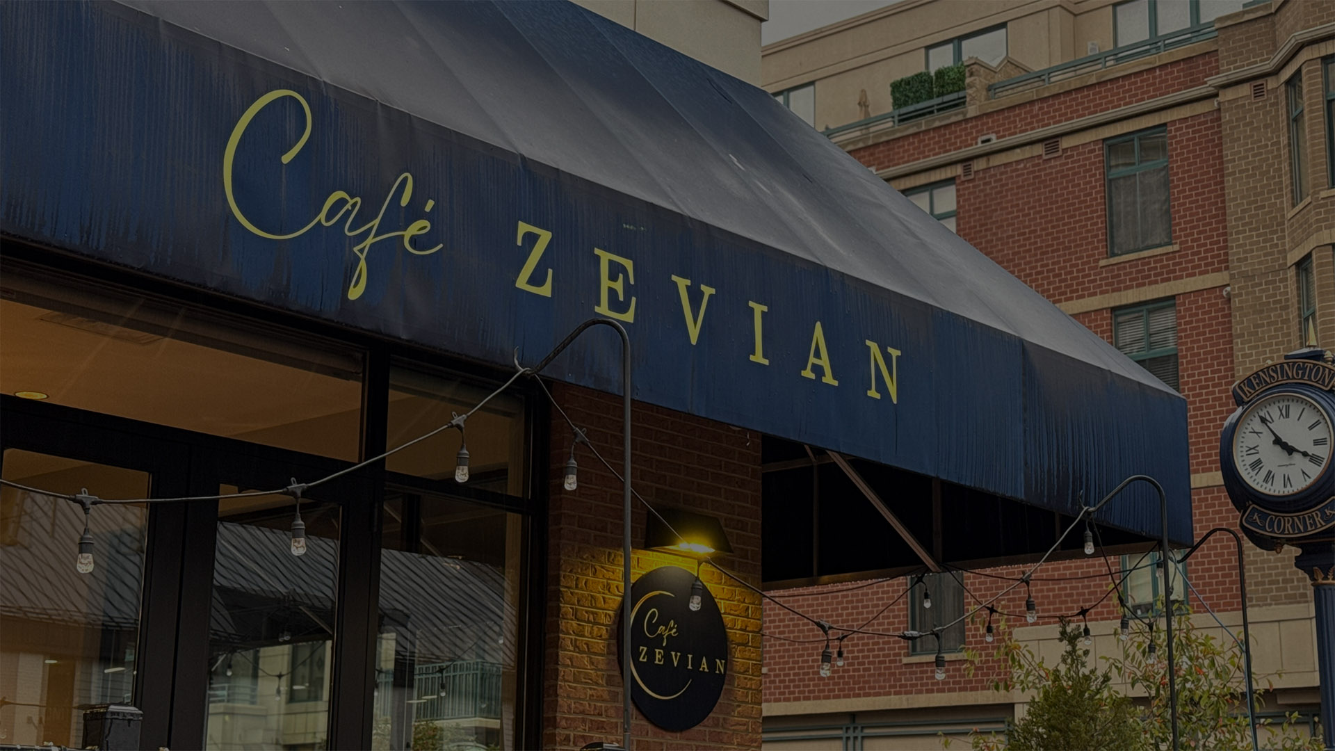 A cafe with a blue awning and yellow sign.